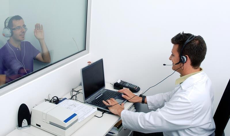 An Audiologist conducts a hearing exam on a relatively young patient. Otosclerosis can contribute towards hearing loss, even in patients aged 20 - 30 yrs old.