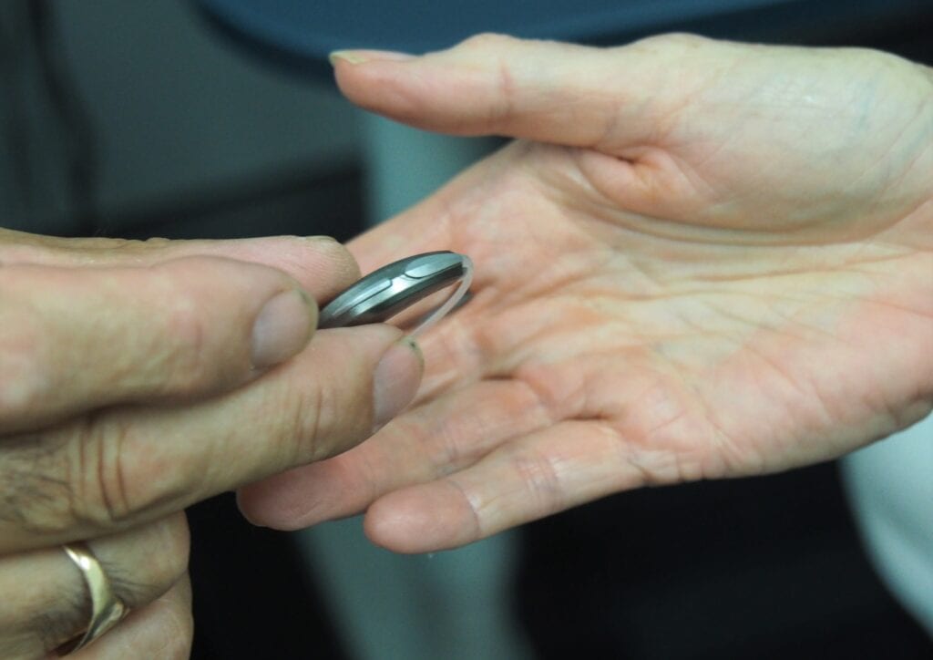 Hearing Aid in Hand- Wearing Hearing Aids