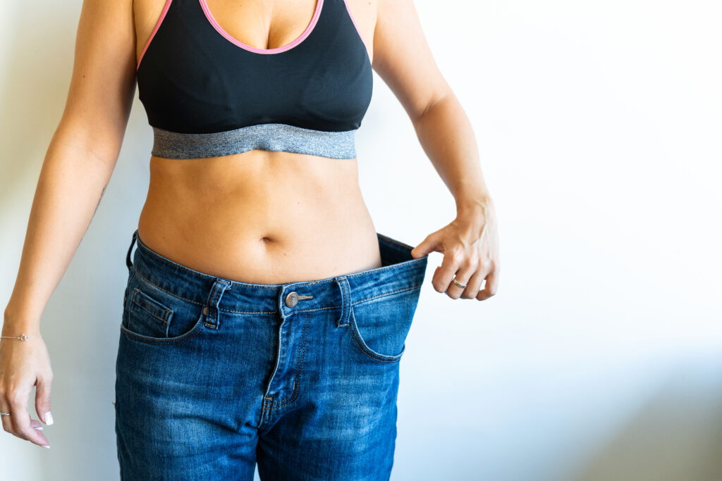 Woman showing weight loss progress in loose-fitting jeans